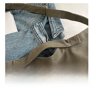 Detail of olive green canvas tote bag with metal adjustment buckle and thick fabric texture