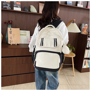Detail of a minimalist black and white backpack with side coin purse in a library setting