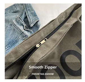 Close-up of smooth metal zipper and durable canvas stitching on army green crossbody bag