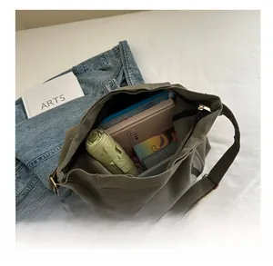 Spacious interior of army green canvas messenger bag holding an umbrella and books