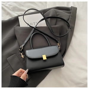 Detail of minimalist black leather crossbody bag with square gold buckle on a stylish suit