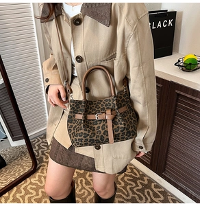 Detailansicht der Handtasche mit Leopardenmuster, braunen Ledergriffen und Beschlägen