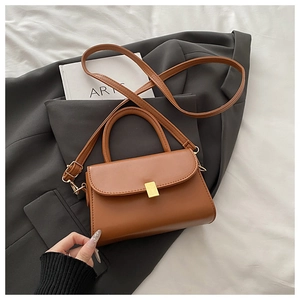 Close-up of brown vintage square bag with gold metal buckle and smooth faux leather texture
