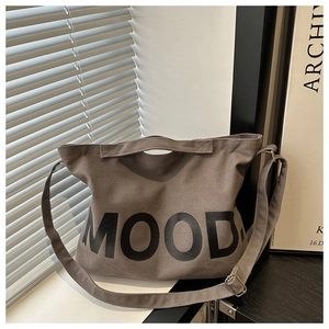 Dettaglio della borsa tote in tela grigia con testo MOOD su sfondo minimalista