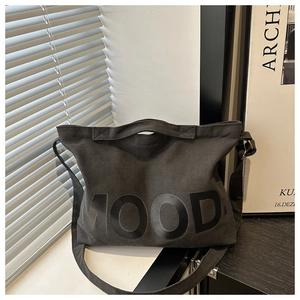 Dettaglio della scritta MOOD su una borsa tote in tela grigio scuro con cinghie