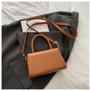 Close-up of caramel leather vintage mini square bag on a stylish grey blazer background