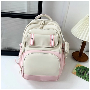Pink and cream canvas backpack with multiple pockets and mini pouch on a desk