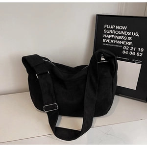 Detail of black canvas tote bag showing wide shoulder strap and silver metal buckle