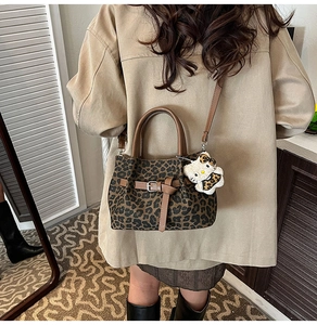 Detail der Leopard-Eimertasche mit braunem Lederriemen und Hello Kitty Plüsch-Anhänger