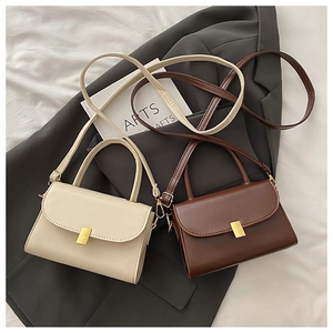 Detail view of stylish white and dark brown crossbody bags with gold metal clasps