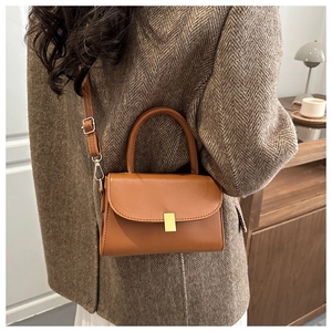 Detail of vintage brown leather handbag with gold clasp and adjustable shoulder strap