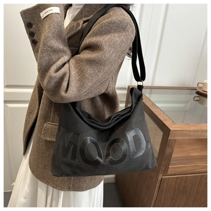Détail du sac bandoulière en toile noire avec lettrage MOOD brillant et sangle