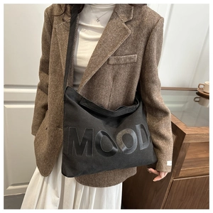 Dettaglio di una grande borsa a tracolla in tela nera con scritta MOOD lucida ed elegante
