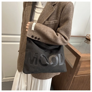 Dettaglio della borsa tote in tela nera con stampa MOOD indossata da una modella
