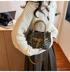 Detail der Leoparden-Beuteltasche mit braunem Lederbesatz, getragen von Frau im beigen Pullover
