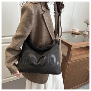 Dettaglio della borsa tote in tela nera con scritta MOOD e styling con blazer