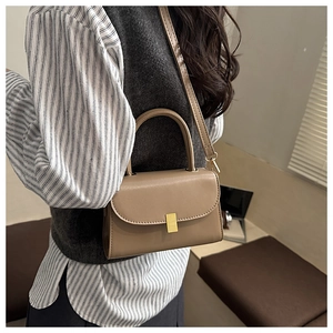Detail of vintage brown leather crossbody bag with golden metal clasp on a model