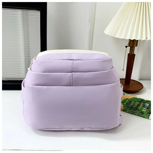 Detail of lavender school backpack showing multi-pocket layers and white color-block design