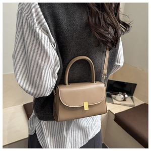 Detail of khaki leather crossbody bag featuring gold metal buckle and sturdy top handle