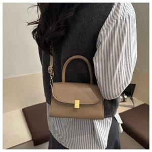 Detail of khaki leather crossbody bag featuring gold metal buckle and thin shoulder strap