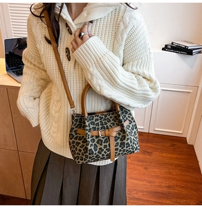 Detail der Leoparden-Beuteltasche mit braunen Ledergriffen auf elfenbeinfarbenem Pullover
