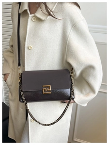 Détail du sac à bandoulière en cuir marron foncé avec fermoir doré et bandoulière