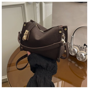 Close-up of dark brown lychee texture leather shoulder bag with golden twist lock detail