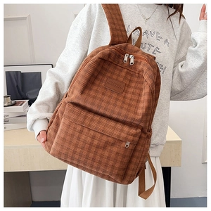 Detail showing vintage brown corduroy backpack with fine grid texture and logo patch