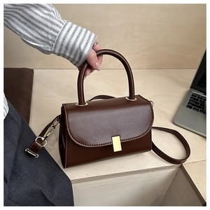Close-up of a dark brown leather crossbody bag with a gold rectangular metal lock