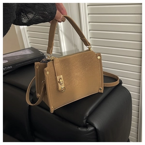 Close-up of khaki satchel bag with golden square twist lock and studded details