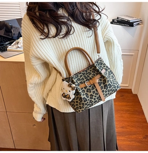 Detail der Handtasche mit Leopardenmuster, braunen Griffen und Plüsch-Anhänger