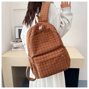 Detail view of brown corduroy backpack showing soft texture and front zipper pocket