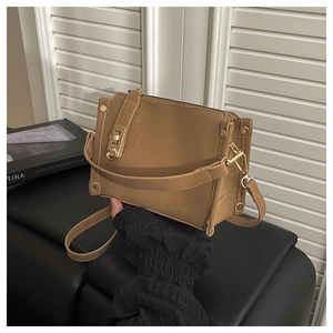 Close-up of brown textured leather small square bag featuring a gold twist lock clasp
