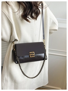 Détail du sac bandoulière marron foncé avec texture cuir mat et fermoir géométrique doré