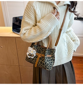 Detailansicht der Beuteltasche mit Leopardenmuster, braunem Riemen und Plüsch-Anhänger