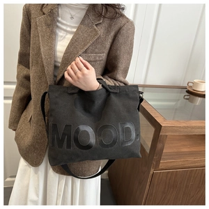 Gros plan du sac cabas en toile noire avec lettrage MOOD brillant dans un décor moderne