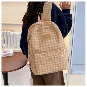 Detail of corduroy plaid backpack in beige showing the front pocket and logo label
