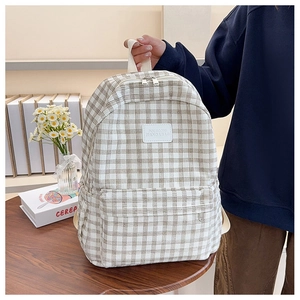 Detail of plaid university backpack with leather logo tag and front zipper pocket