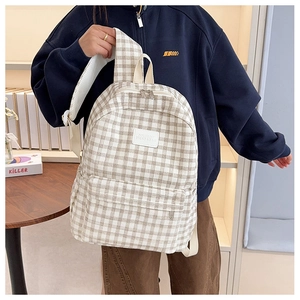 Detail of beige and brown checkered backpack with leather logo and multi-zipper layers
