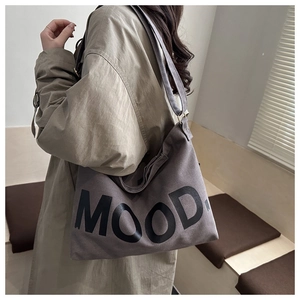 Dettaglio della borsa tote in tela color tortora con stampa MOOD indossata da modella