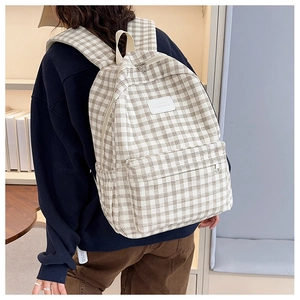 Detail of checkered canvas backpack showing large main pocket and brand logo patch
