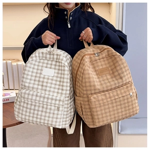 Detail of college style plaid backpacks in beige and brown with woven texture