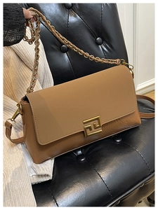 Détail du sac bandoulière vintage marron avec boucle dorée sur banc en cuir