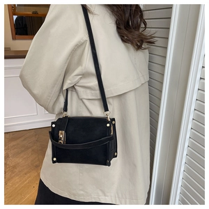 Detail of a vintage black crossbody bag with matte finish and gold square metal clasp