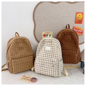 Detailed view of three corduroy plaid backpacks in beige, yellow and brown colors