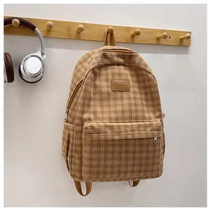 Detailed macro view of brown corduroy backpack with check pattern and leather logo patch
