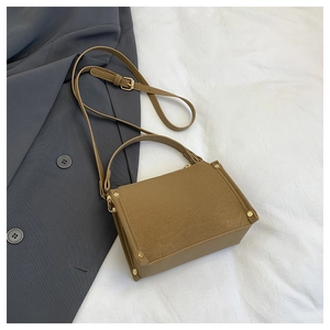 Detail of khaki brown handbag with gold studs on textured faux leather and adjustable strap