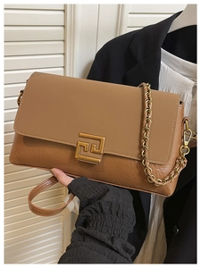 Détail d'un sac à bandoulière marron avec chaîne, textures cuir et fermoir doré
