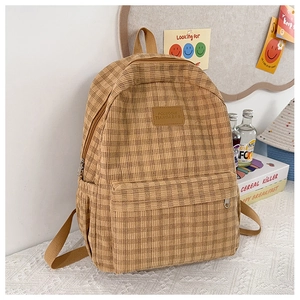 Detail view of yellow plaid corduroy backpack on a white lace tabletop with lifestyle decor