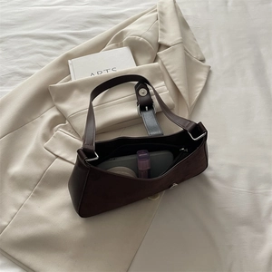 Brown leather crescent shoulder bag with silver buckle on minimalist neutral background